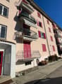 multi-family apartment building, balconies, red doors, mailbox area, fenced in front