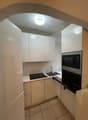 Modern kitchen with white cabinets, tile flooring, microwave, sink, gas stove, and oven
