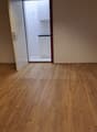 Empty room with open door to a smaller room with bathroom, wooden floor, white walls