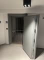 Entrance with metal gate, small hallway, tiled floor, and metal ceiling fixtures.
