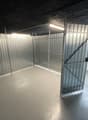 Empty room with metal walls, concrete floor, and two metal doors.