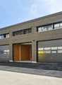 Industrial building with multiple garages, gray exterior, windows, and an open garage door.