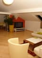 white leather couches, wooden coffee table, TV, potted plant, wooden floor, dining table and chairs, kitchen area