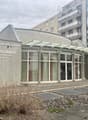 Building exterior of Christian Science with entrance, concrete wall, glass windows, glass doors, and bicycle parked outside.