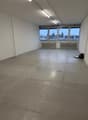 empty room with windows, concrete floor, mounted lights, radiators, white walls