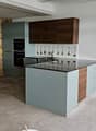 kitchen island, countertop, stone wall, cabinets, built-in oven, sink, faucet, large open room, white flooring
