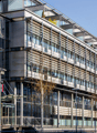 Gray building, large windows, metal railings, balcony, glass entrance, street lamp