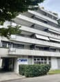 multi-story building, balconies, windows, air conditioners, entrance, sign
