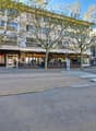 A building with many windows, a restaurant named Les Brasseur, a bench, and trees in front.