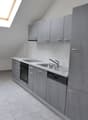 empty kitchen with light tile flooring, grey cabinets, stainless steel sink, dishwasher
