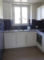 U-shaped kitchen with white cabinets, blue tile backsplash, and stainless steel appliances including a dishwasher.