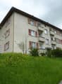 4 story apartment building, red shutters, white walls, located on a slope