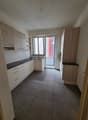 empty kitchen with tiles floor, white cabinets, black countertops, and stainless steel sink and faucet