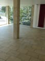 large empty room with large windows, tiled floor, large pillar, white walls