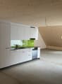 A kitchen with a white wooden ceiling, kitchen appliances, wooden panels on the walls, countertops, sinks and cabinets