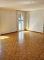Empty room with double doors, large windows, wooden parquet floor, white walls