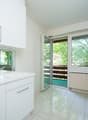 ein modernes Badezimmer mit weißen Schränken, einem großen Fenster und einer Glasschiebetür zu einem anderen Raum / a modern bathroom with white cabinets, a large window and a sliding glass door t