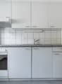 White cabinets, granite countertop, tiled backsplash, stove, dishwasher