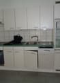 white cabinets, green countertop, stainless steel sink, dishwasher, refrigerator, oven, tiled walls