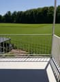 balcony with white railings, floor, open view of field, some trees