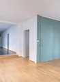 empty room with wooden floors, white and green walls, radiators, and multiple windows