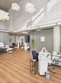 Interior design with white walls, wooden floor, multiple white chairs, lamps, desk, plants