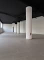 Empty room, white walls, black ceiling, gray tile floor, large windows, pillars