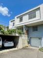 white 2 story house, garage for 2 cars, steps to the entrance, covered parking area, plants on the wall