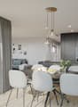 Spacious open-concept living area with a dining table, gray upholstered chairs, and a modern kitchen with dark cabinets and appliances. Large windows and sliding glass doors provide access to a balcony or terrace. The room is decorated with artwork and po
