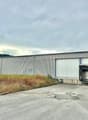 Large industrial building with one main entrance, a large opening on the side, and a smaller building next to it. Parking lot in front.