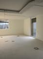 Empty room with white walls and floors, sliding door, two windows, pipes on the ceiling