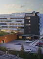 Contemporary design hotel, multiple floors, underground parking, outdoor terrace, public transport nearby, mountains in the background.