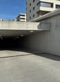 Concrete underground parking with several ceiling lights, entrance ramp and drainage system