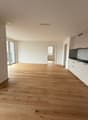 Empty room with wooden floor, white walls, glass doors, white kitchen cabinets, black oven, white ceiling