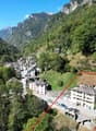 Stone building in a mountainous area, white facade, located on the edge of the road, several trees