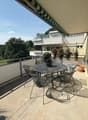 outdoor dining table with chairs, railing, plants, view of greenery