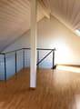 empty attic room, wooden floor, white walls, metal railings, skylight