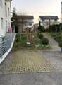 Brick paved area with greenery, a small hill in the middle, concrete pavements