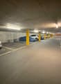 concrete floor, yellow pillars, multiple cars parked, empty spaces