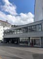 2 story building with large windows, car park in front, cars parked inside