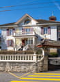2 story house, multiple windows, balcony, stone fence, gate, no visible garage or pool