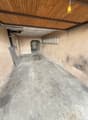 Empty concrete floor, wooden ceiling, ladder on the wall, small hole in the wall