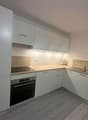 modern kitchen with white cabinets, wooden countertops, integrated oven and dishwasher, sink with faucet, power outlets