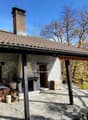 Stone house, chimney, fireplace, wooden porch, wooden storage boxes, logs, plants