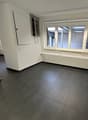 empty room, white walls, tiled floor, large windows, radiator, wiring equipment in corner
