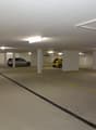 Empty parking area, underground, with yellow markings on the floor and white pillars, 4 cars parked