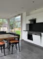 dining area with a wooden table and chairs, white cabinets, black countertops, oven, dishwasher, glass windows