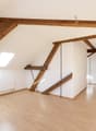 empty room, wooden beams, wooden floor, white walls, radiator, skylight