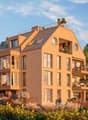4 story apartment building, large windows, balconies, beige walls, rooftop terrace