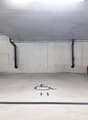 underground parking garage, concrete walls, white floor, designated parking spot number 11